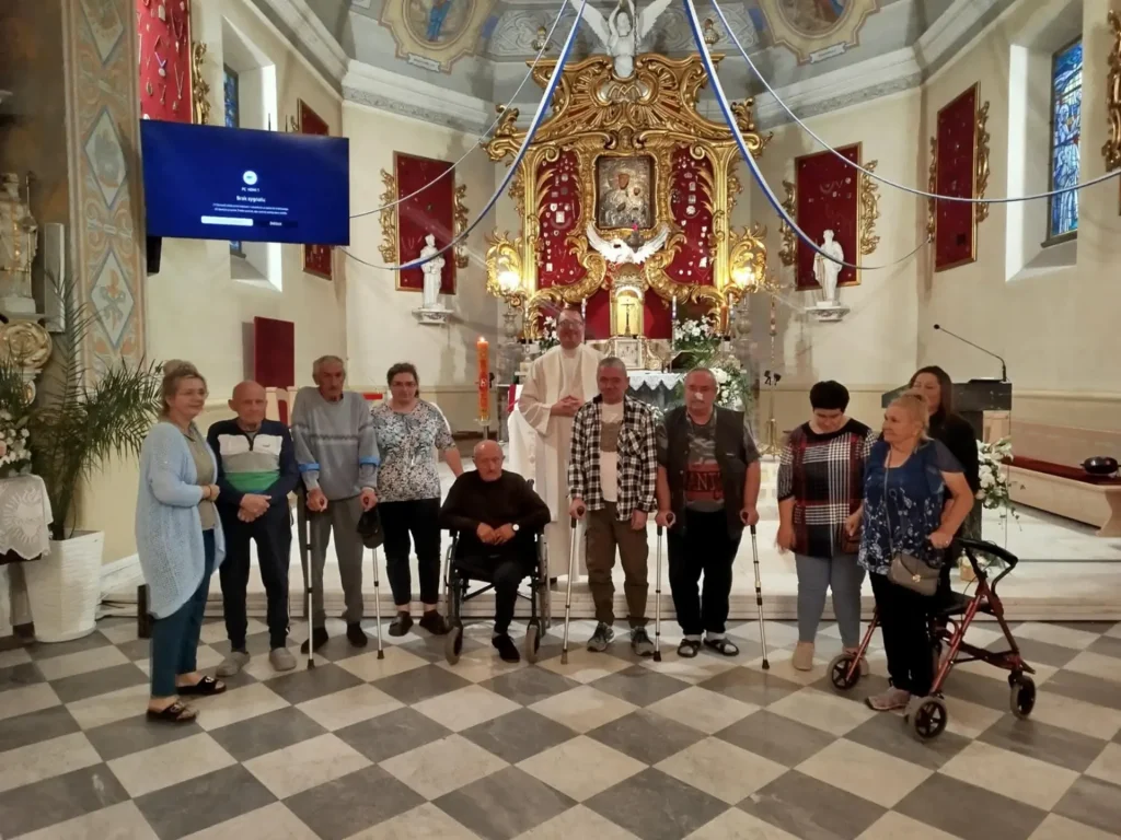 Uczestnicy Dziennego Domu Pobytu z księdzem przed ołtarzem w kościele podczas wycieczki
