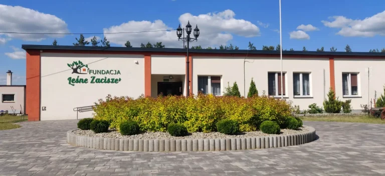 Budynek schroniska Fundacji Leśne Zacisze w Sokołowym Kącie z logo na elewacji i klombem przed wejściem