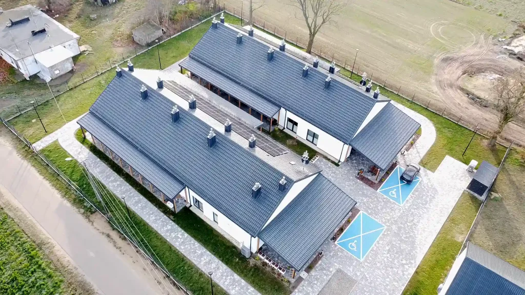 Dwa parterowe budynki Wspomaganych Społeczności Mieszkaniowych w Kraszewie Gaczułty widziane z drona